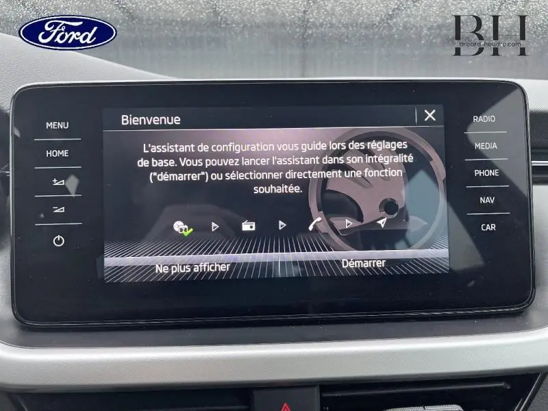 Écran tactile central du tableau de bord d'un Skoda Kamiq rouge Velvet, affichant l'assistant de configuration.