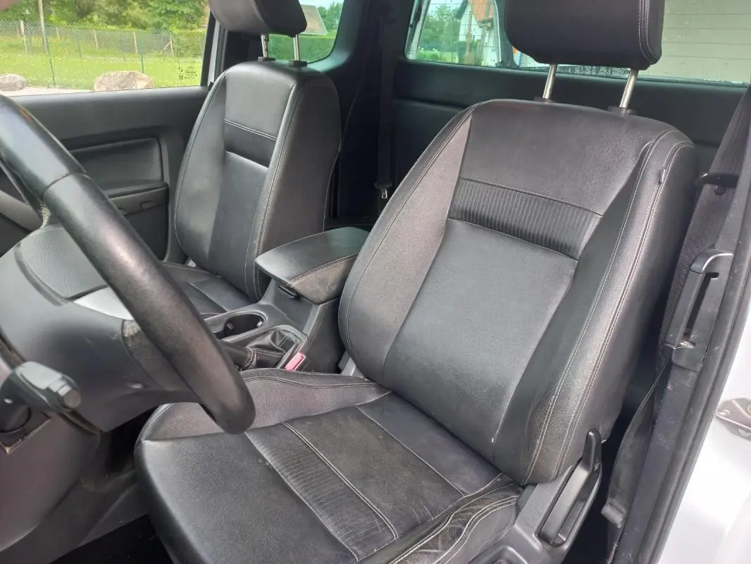 Vue intérieure côté conducteur du Ford Ranger blanc 2022, sièges en cuir noir et volant visible.