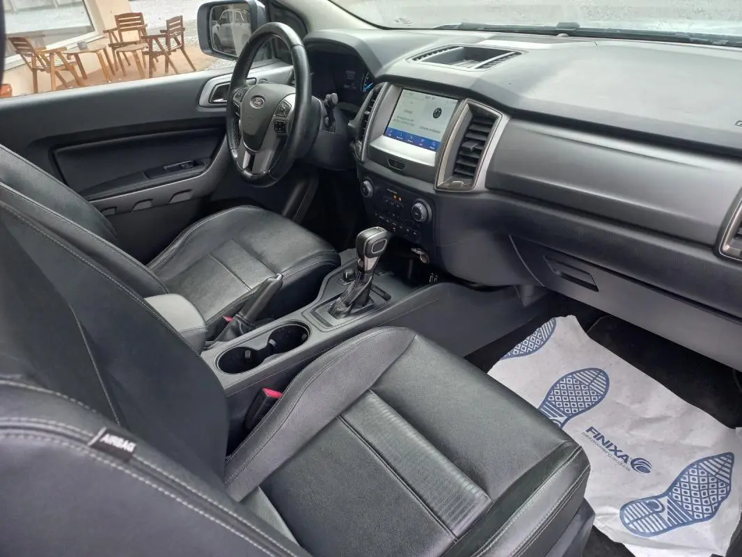 Vue intérieure côté conducteur du Ford Ranger blanc 2022, mettant en valeur les sièges cuir noirs et la console centrale avec boîte automatique.