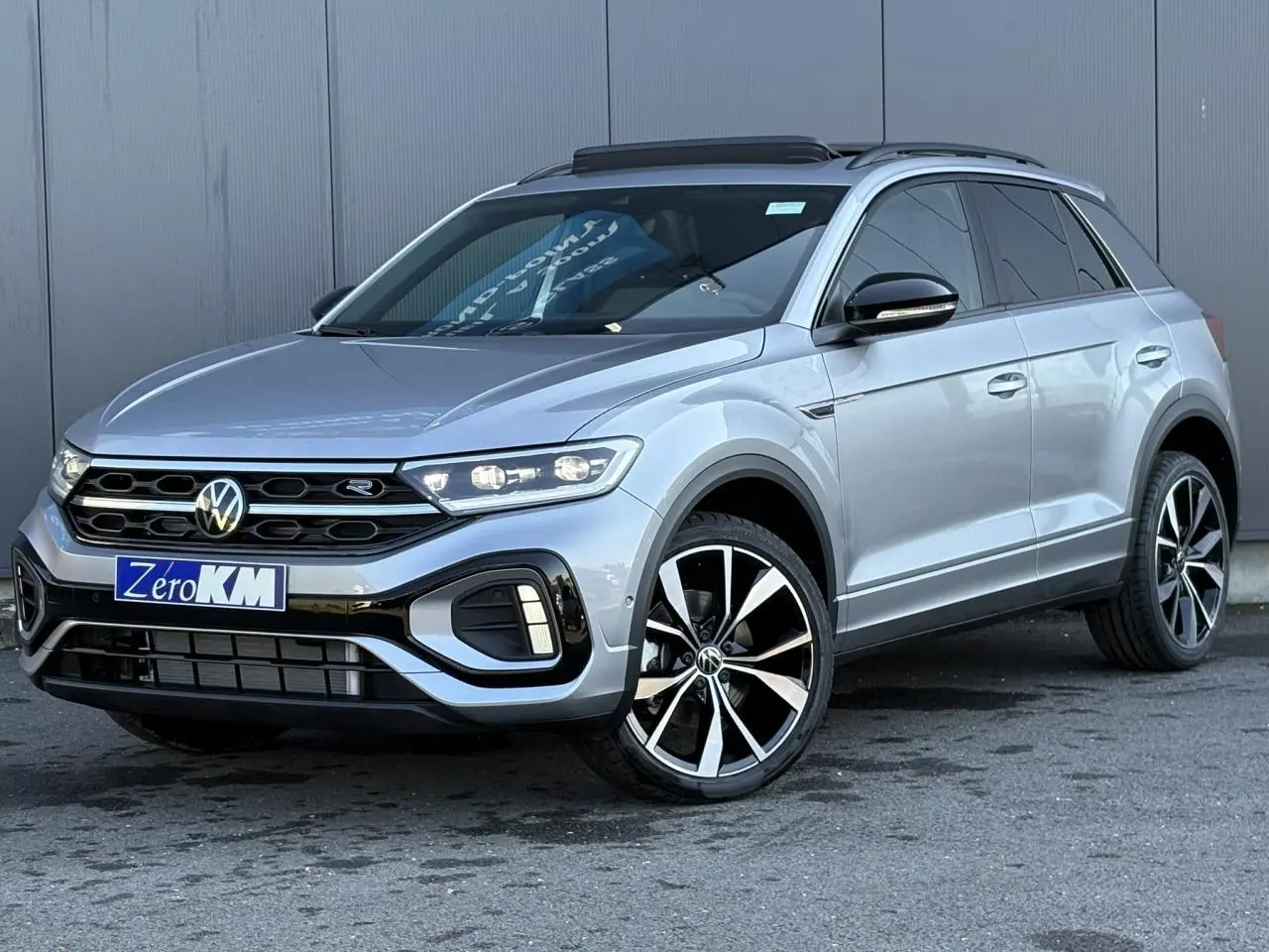 Volkswagen T-Roc gris pyrite en 3/4 avant droit avec jantes alliage 19" et toit ouvrant ouvert.