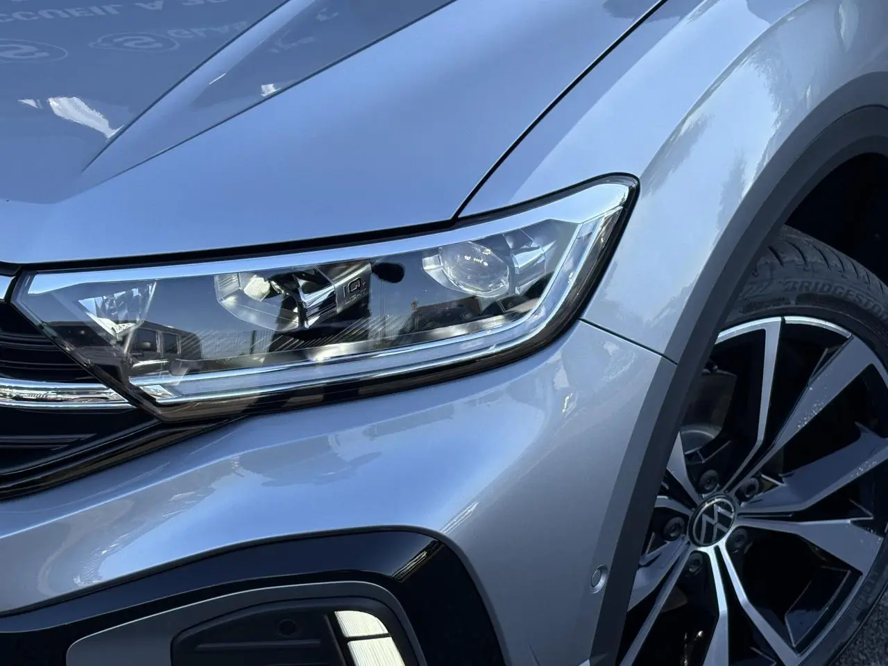 Gros plan sur l'avant droit gris pyrite du Volkswagen T-Roc 2025 avec phare LED et jante alliage noir et argent.