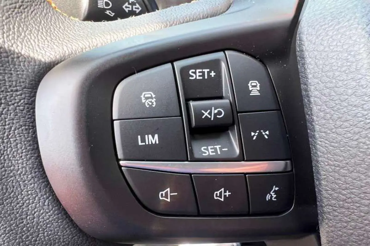 Gros plan sur les commandes au volant du Ford Ranger 3.0 V6 240 Wildtrak Plus noir agate, boutons de régulateur et volume.