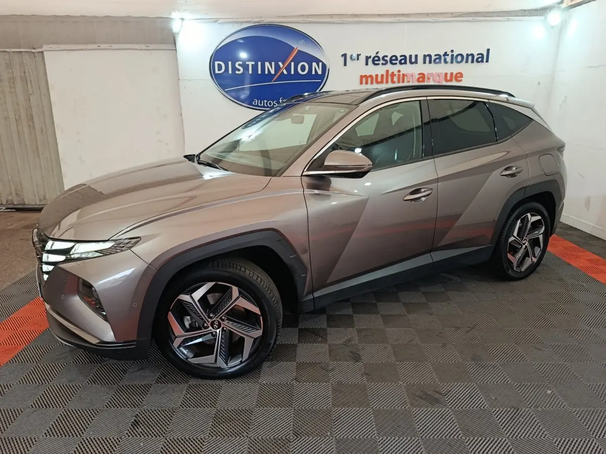 Vue 3/4 avant droit du Hyundai Tucson marron 2022 hybride rechargeable avec jantes modernes et lignes anguleuses.