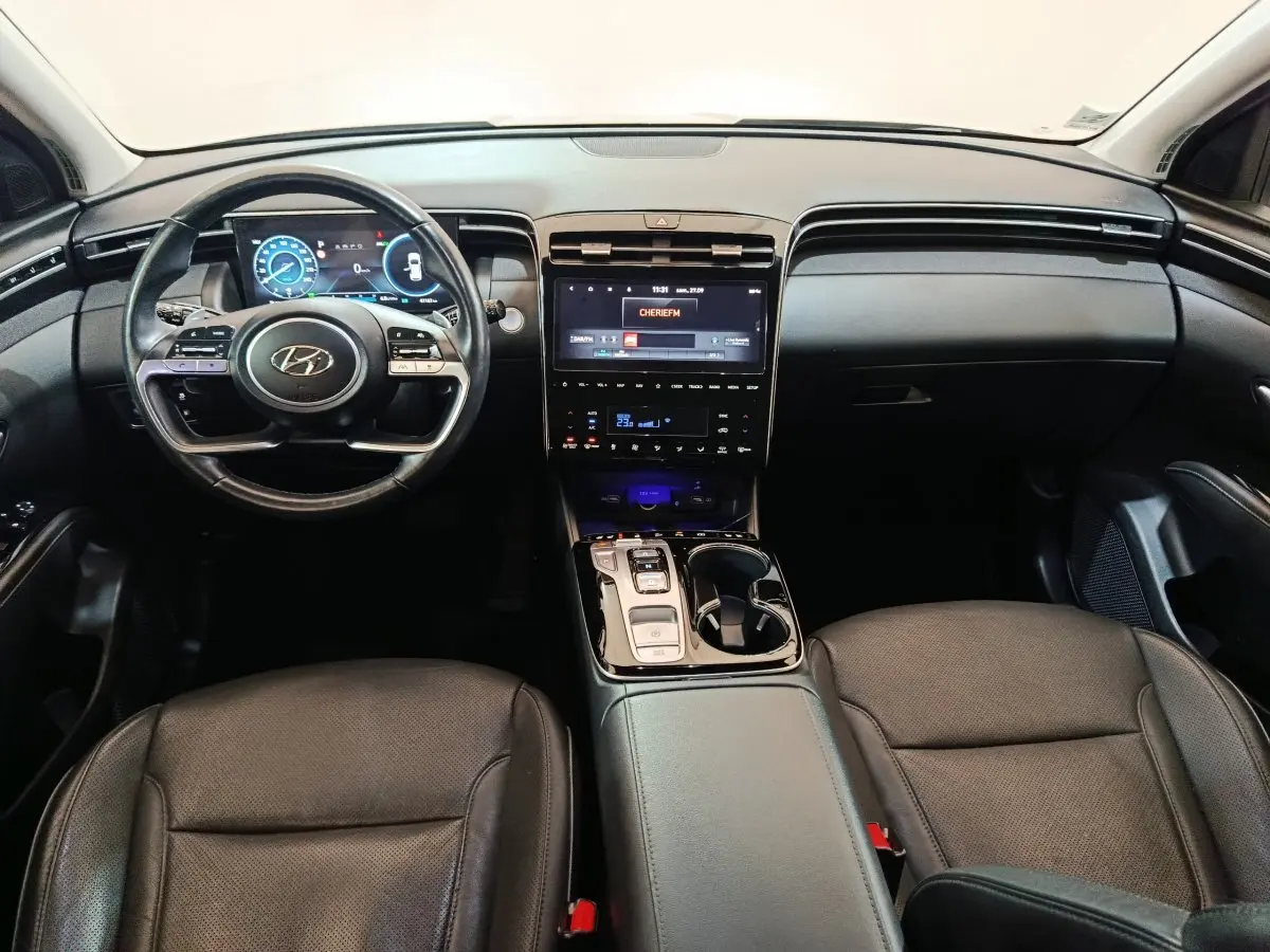 Intérieur noir du Hyundai Tucson 2022, vue frontale du tableau de bord avec écran tactile et volant multifonction.