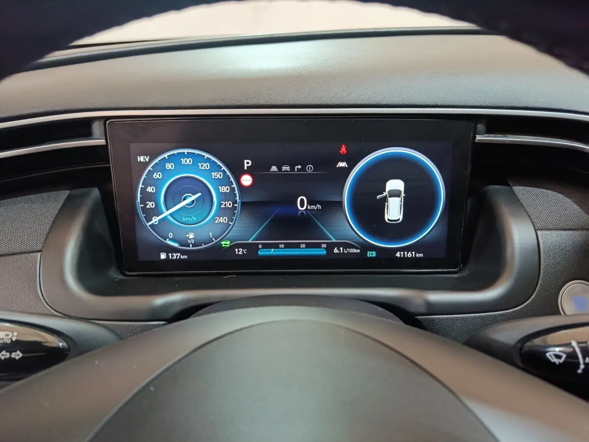 Tableau de bord numérique du Hyundai Tucson 2022 montrant vitesse et alertes, vue depuis le volant.