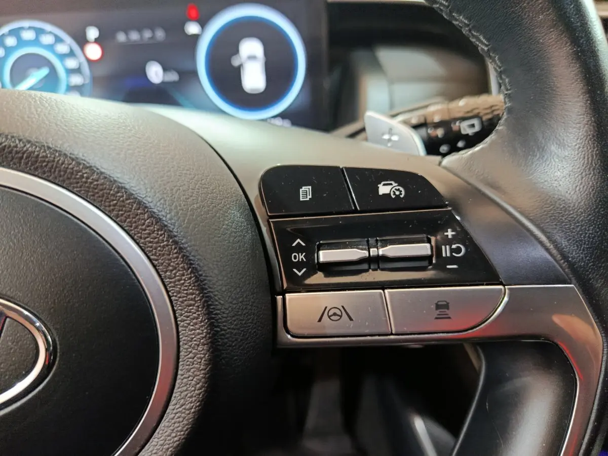 Gros plan sur les commandes du volant côté droit du Hyundai Tucson marron hybride rechargeable 2022 avec affichage digital.