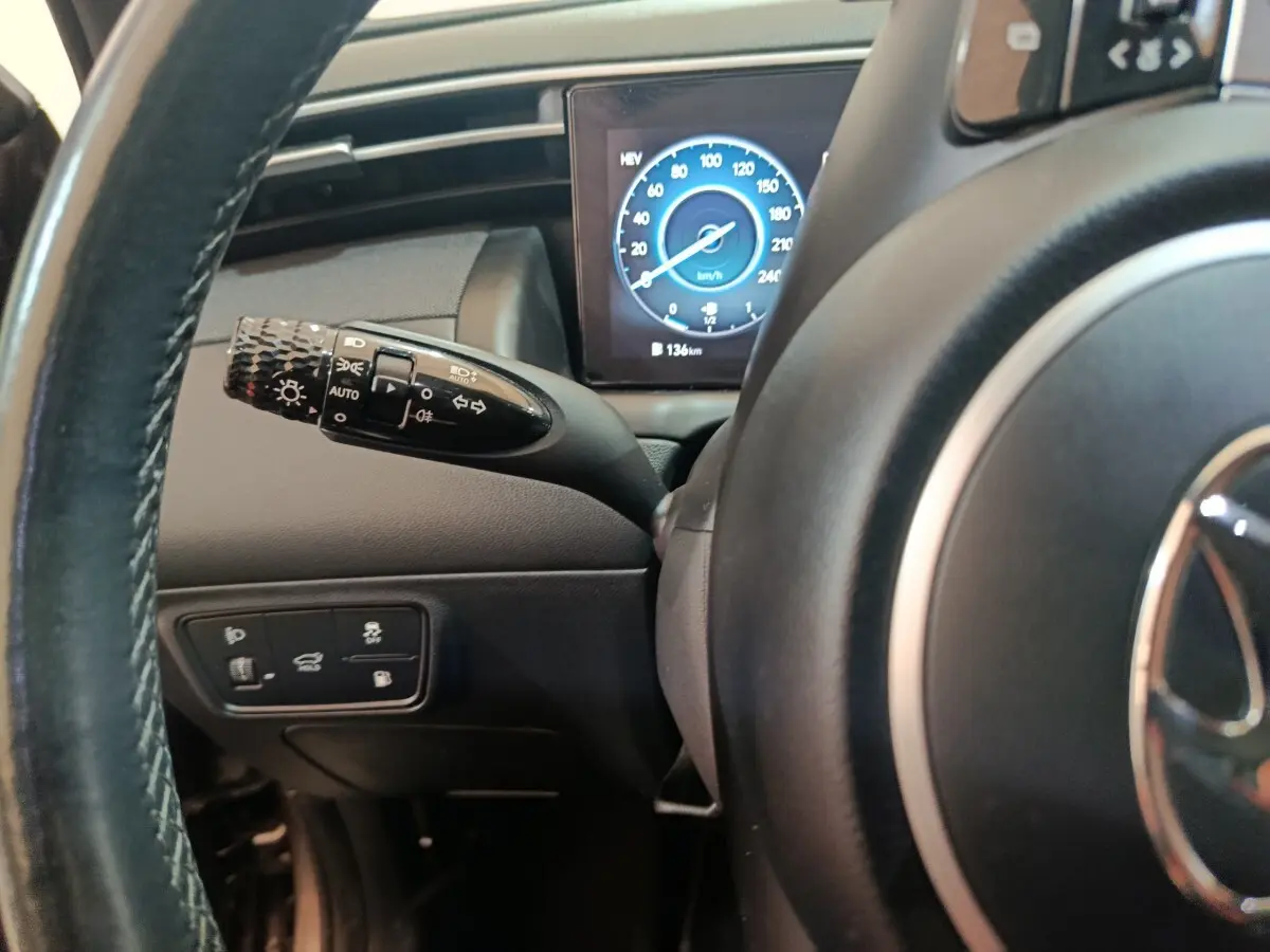 Gros plan sur le volant et le commodo gauche du Hyundai Tucson marron 2022, avec tableau de bord numérique affichant la vitesse.