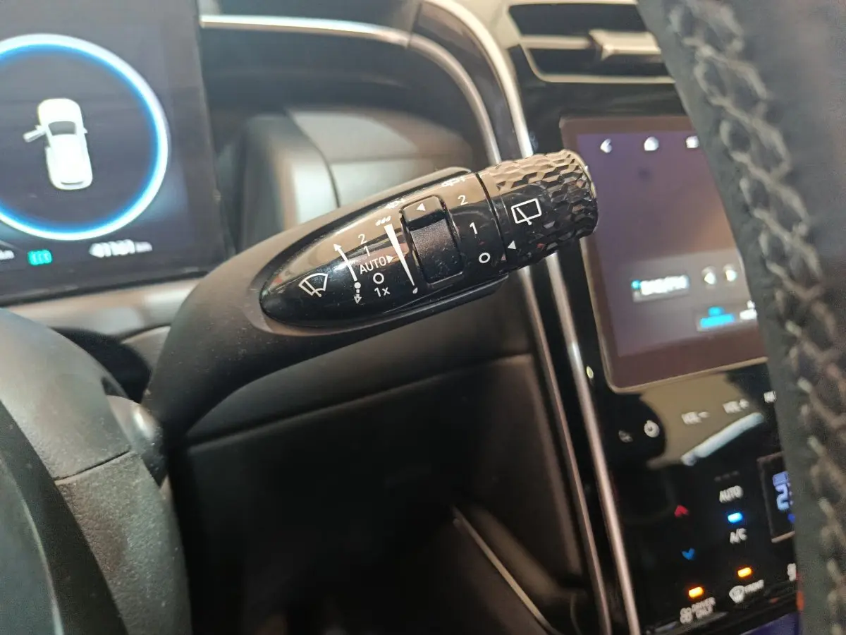 Gros plan sur la commande d'essuie-glace noire du Hyundai Tucson 2022, avec tableau de bord et écran tactile en arrière-plan.