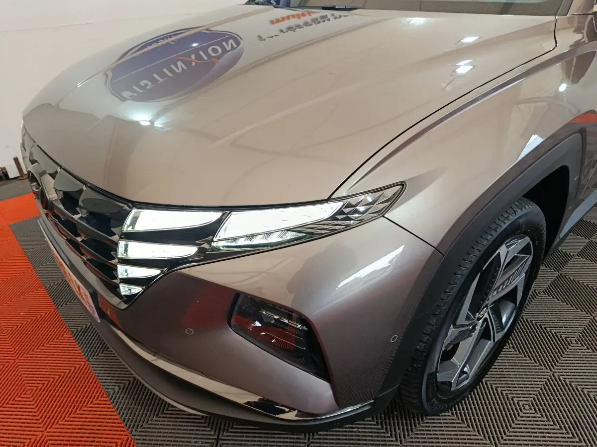 Vue 3/4 avant droit du Hyundai Tucson marron avec ses phares LED et jante alliage distinctifs.