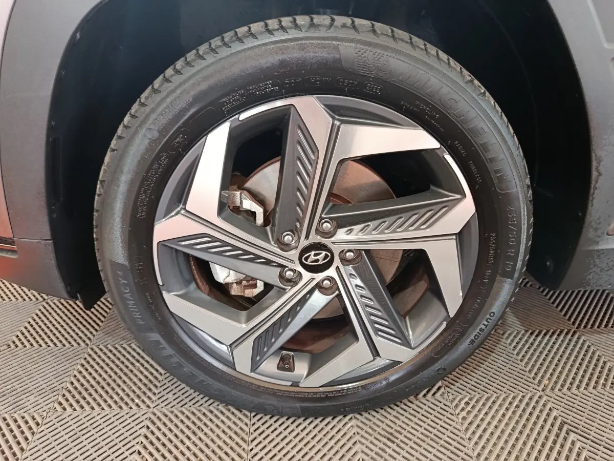 Gros plan sur la roue avant droite marron du Hyundai Tucson 1.6 PHEV 265 HTRAC avec jante alliage design moderne.