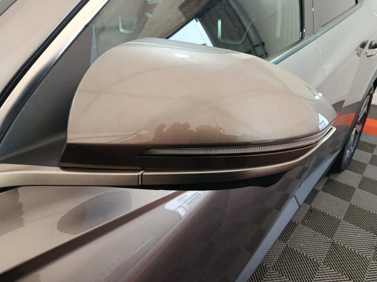 Rétroviseur côté gauche marron du Hyundai Tucson 2022, avec clignotant intégré et carrosserie partiellement visible.