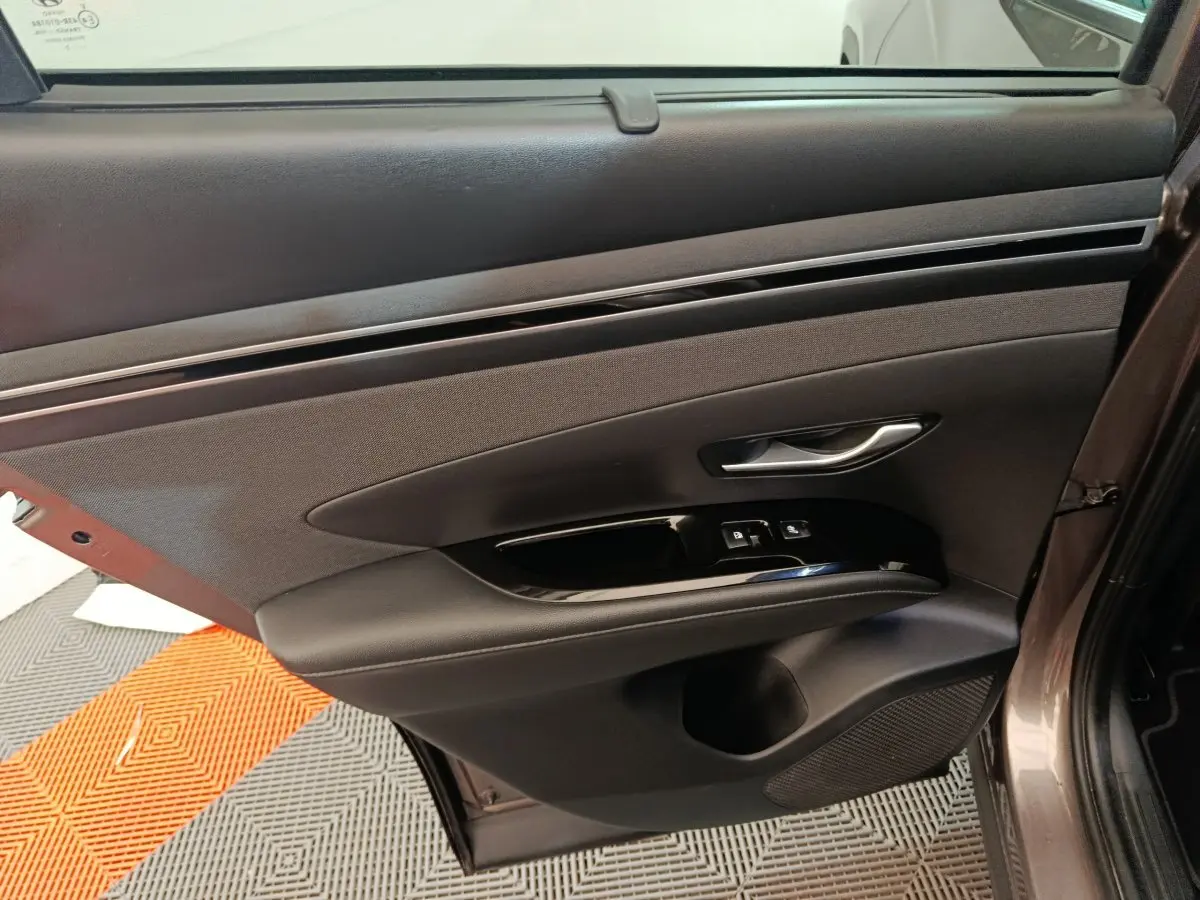 Porte arrière droite intérieure marron du Hyundai Tucson 2022 avec poignée argentée et commandes de vitres.