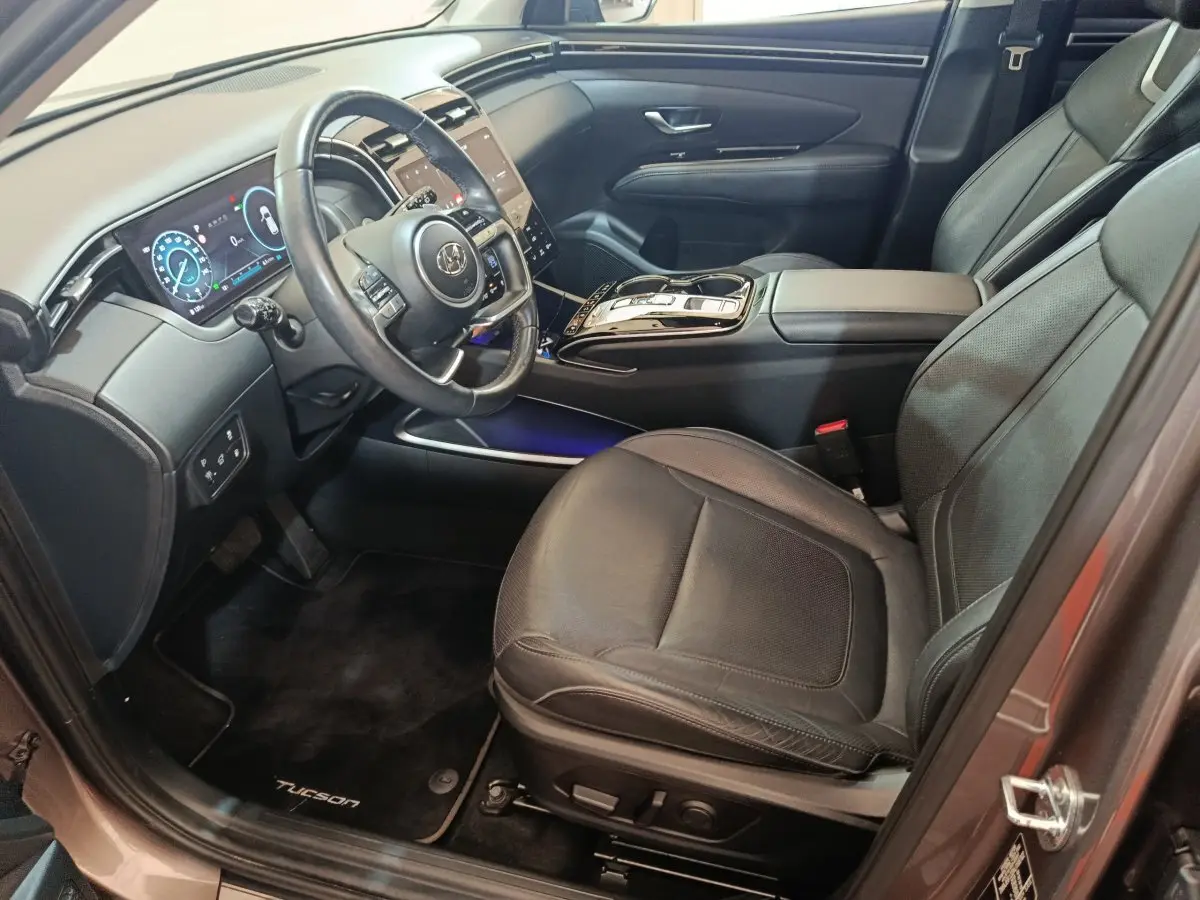Intérieur côté conducteur du Hyundai Tucson marron 2022, mettant en valeur le volant cuir multifonctions et l'écran digital.