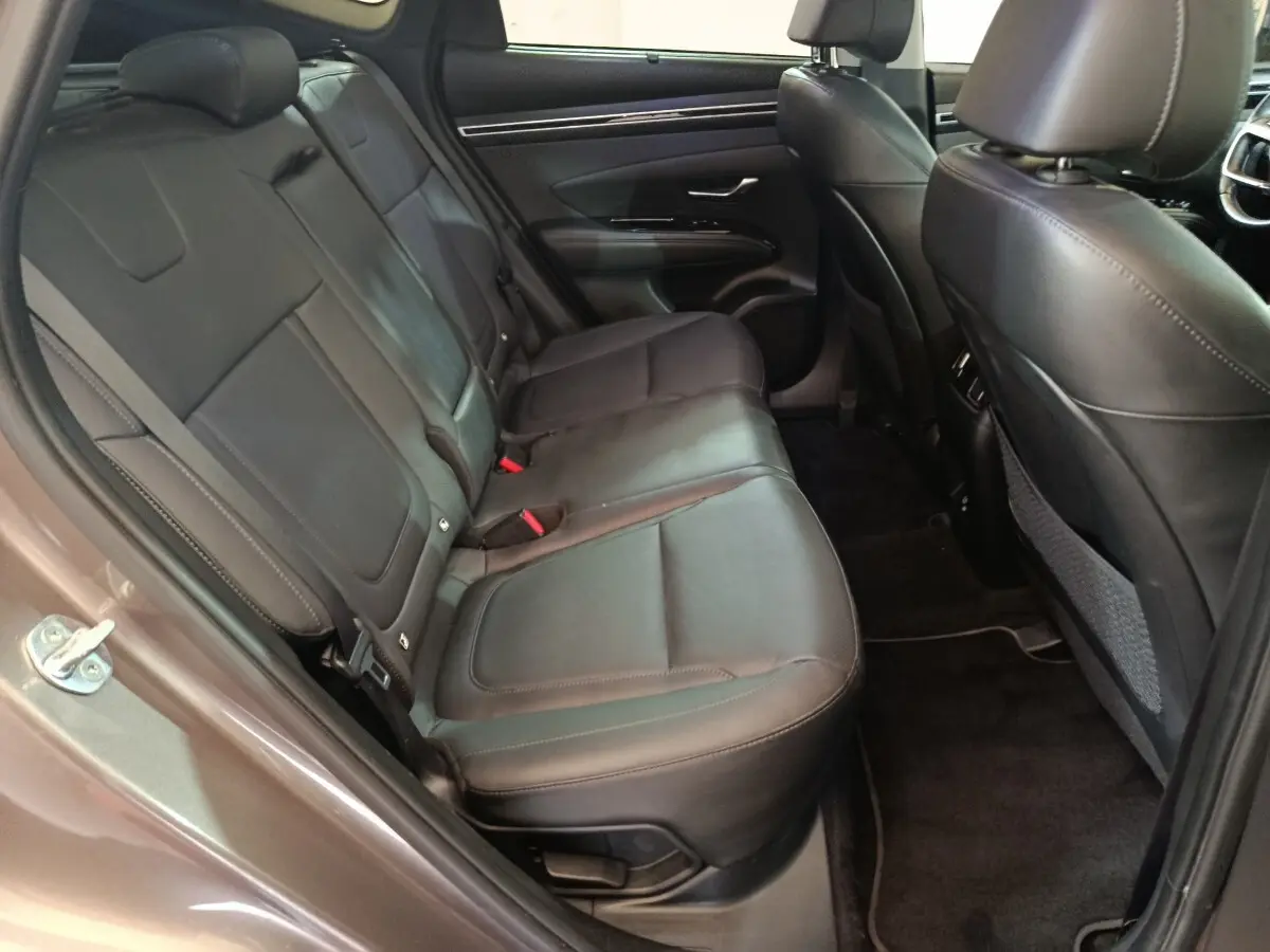 Vue intérieure côté gauche des sièges arrière en cuir noir du Hyundai Tucson marron 2022, avec porte ouverte.