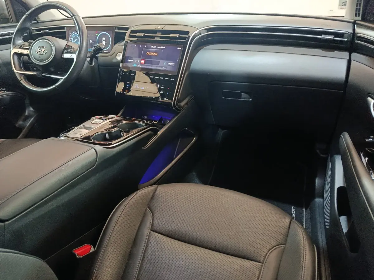 Intérieur noir du Hyundai Tucson 2022 vu côté passager, avec tableau de bord et écran tactile central lumineux.