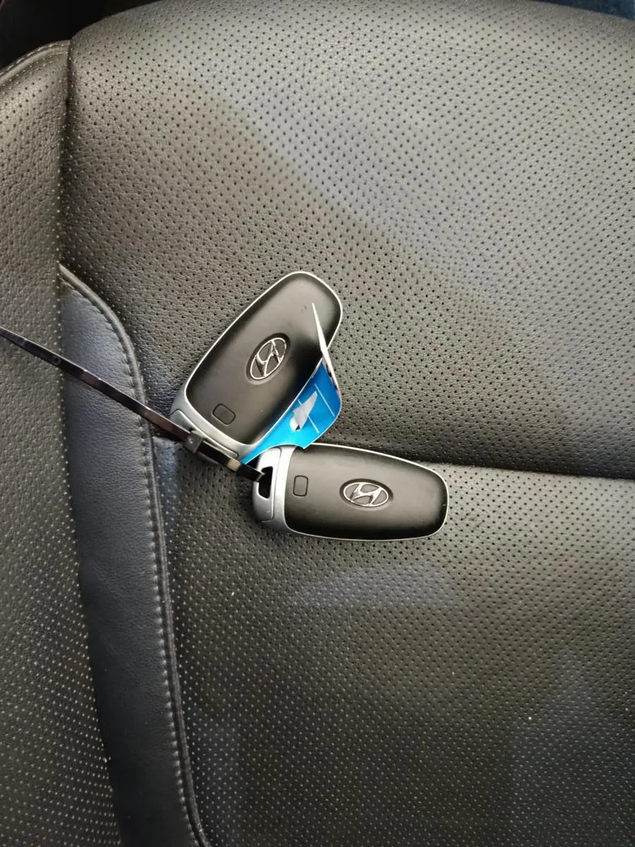 Gros plan sur deux clés Hyundai posées sur un siège en cuir noir perforé, intérieur du Tucson hybride rechargeable.