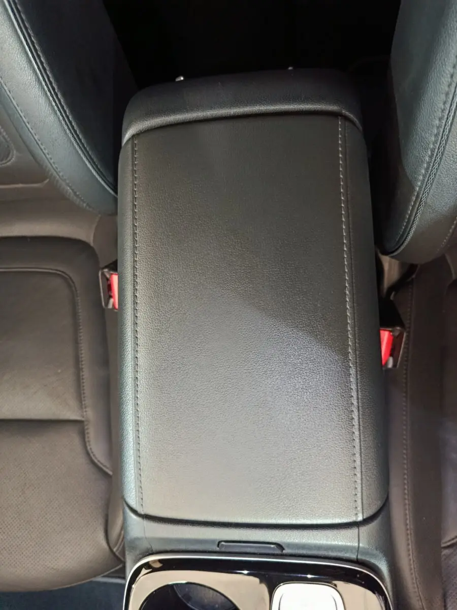 Vue plongeante sur l'accoudoir central en cuir noir de l'habitacle du Hyundai Tucson marron 2022 hybride rechargeable.