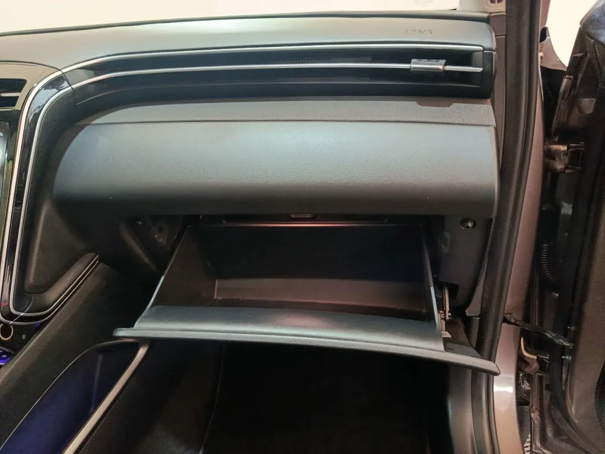 Gant de rangement ouvert côté passager dans l'habitacle noir du Hyundai Tucson marron 2022 hybride rechargeable