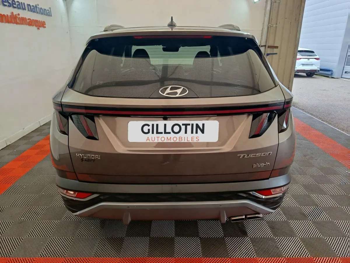 Vue arrière d'un Hyundai Tucson marron plug-in hybride avec feux LED et double sortie d'échappement visible.