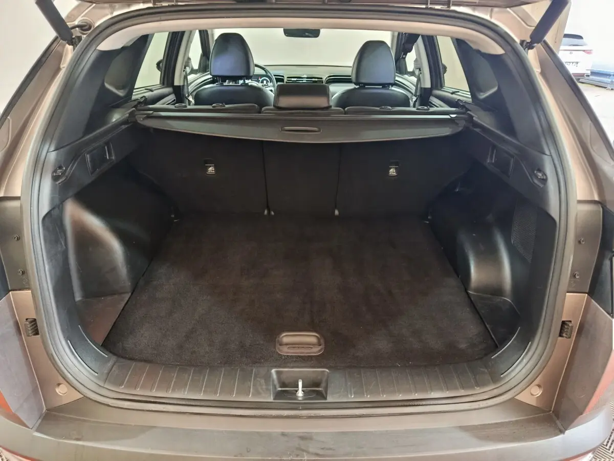 Coffre ouvert vu de l'arrière d'un Hyundai Tucson marron 2022, montrant l'espace de chargement et la plage arrière.