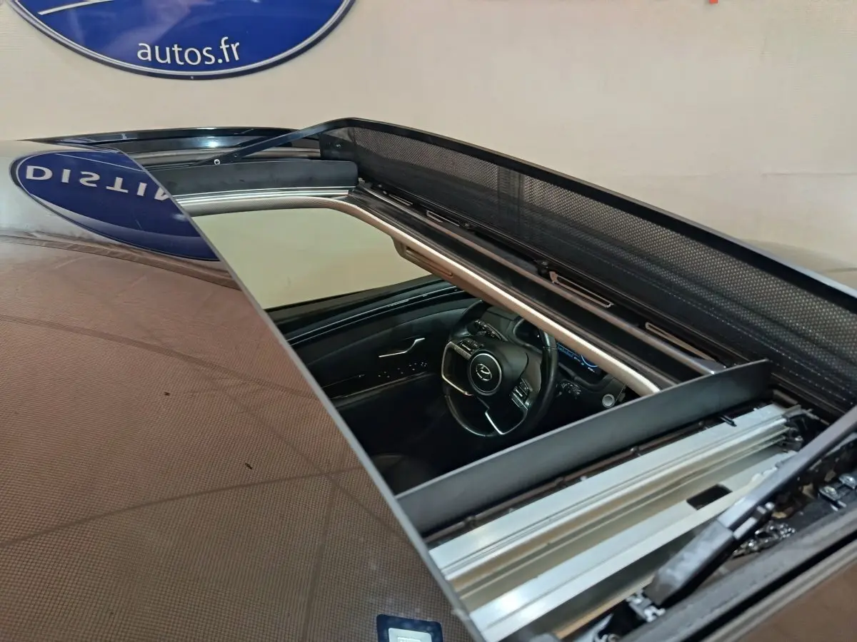 Vue plongeante sur l'intérieur du Hyundai Tucson marron 2022, avec toit ouvrant et volant multifonctions visible.