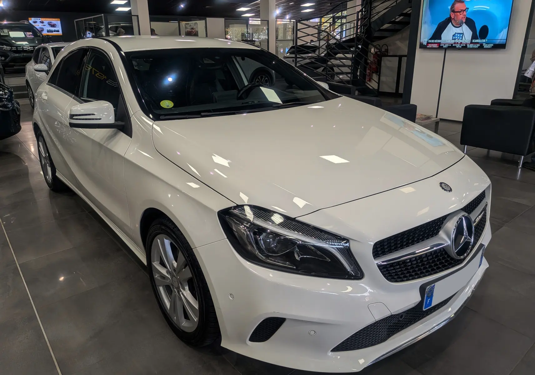 Mercedes Classe A 200d blanc vue 3/4 avant droit dans un showroom avec jantes alliage et calandre chromée.