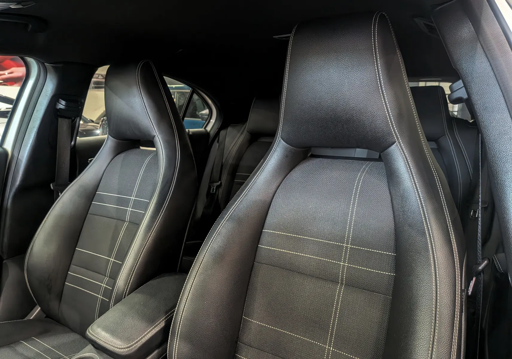 Gros plan sur les sièges avant en cuir noir avec surpiqûres blanches de la Mercedes Classe A 200d 2016.