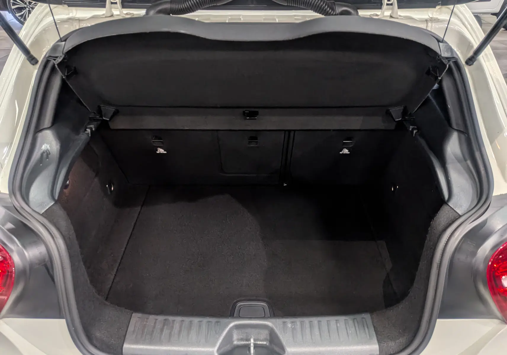 Coffre ouvert vu de dessus d'une Mercedes Classe A 200d blanche de 2016, montrant l'espace de chargement vide et noir.