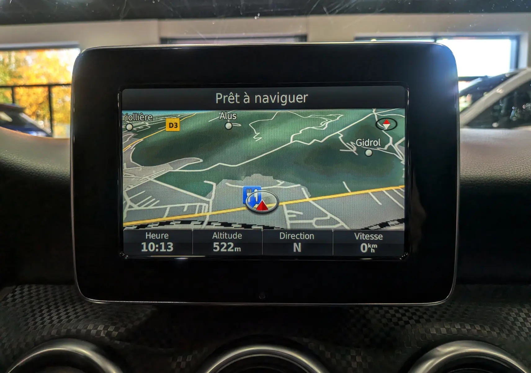 Écran de navigation allumé dans le tableau de bord d'une Mercedes Classe A blanche, vue intérieure frontale.