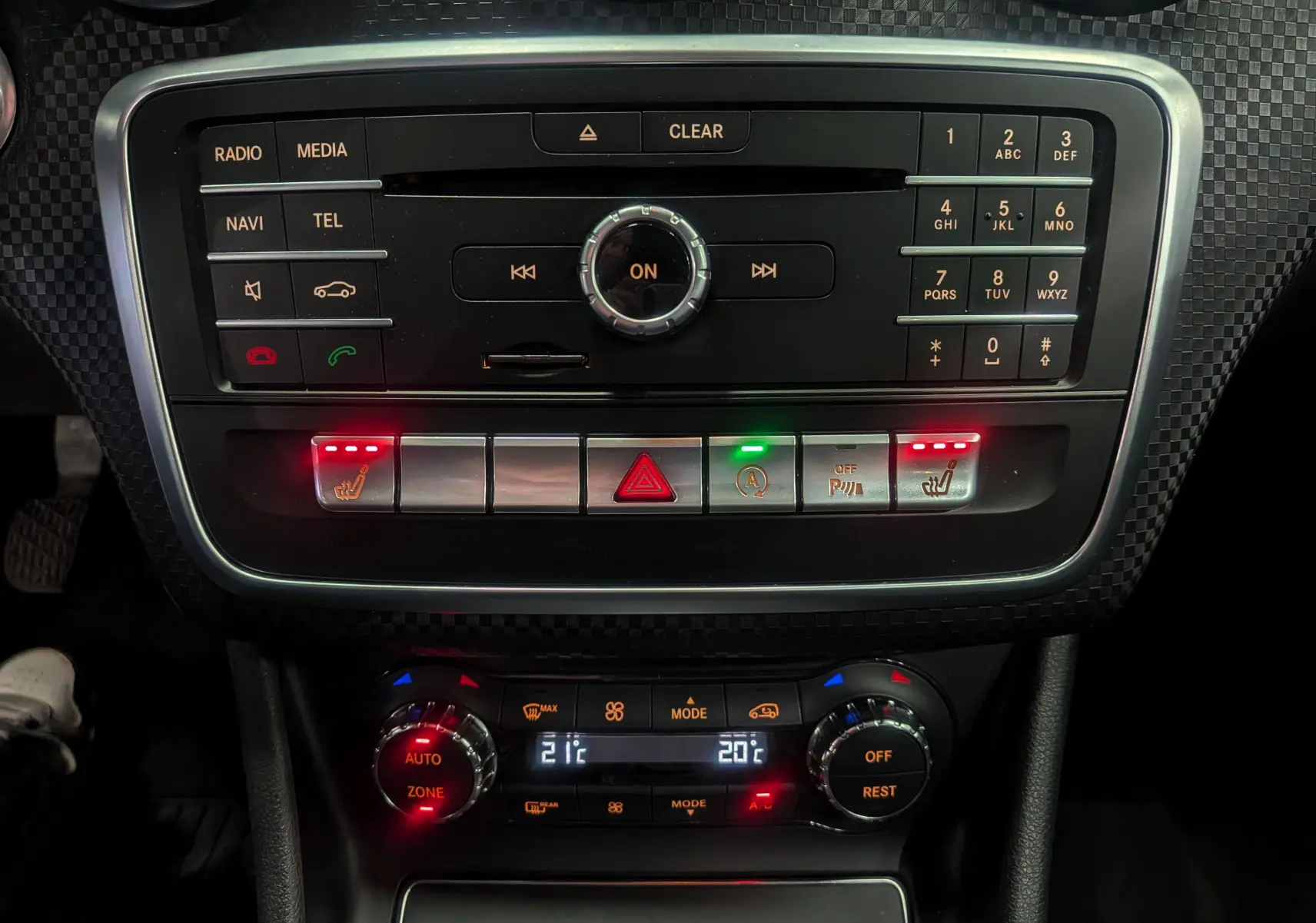 Console centrale de Mercedes Classe A 200d 2016 avec commandes radio, climatisation bi-zone et sièges chauffants activés.