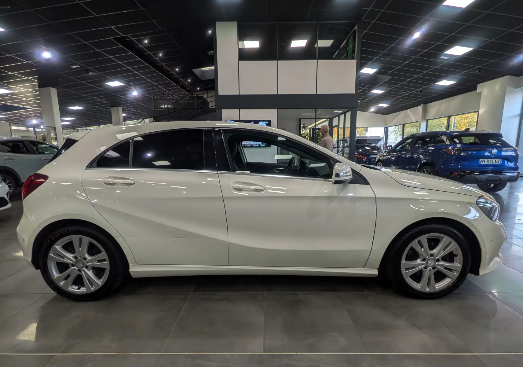 Profil côté gauche d'une Mercedes Classe A 200d blanche en intérieur, soulignant ses lignes épurées et jantes alliage.