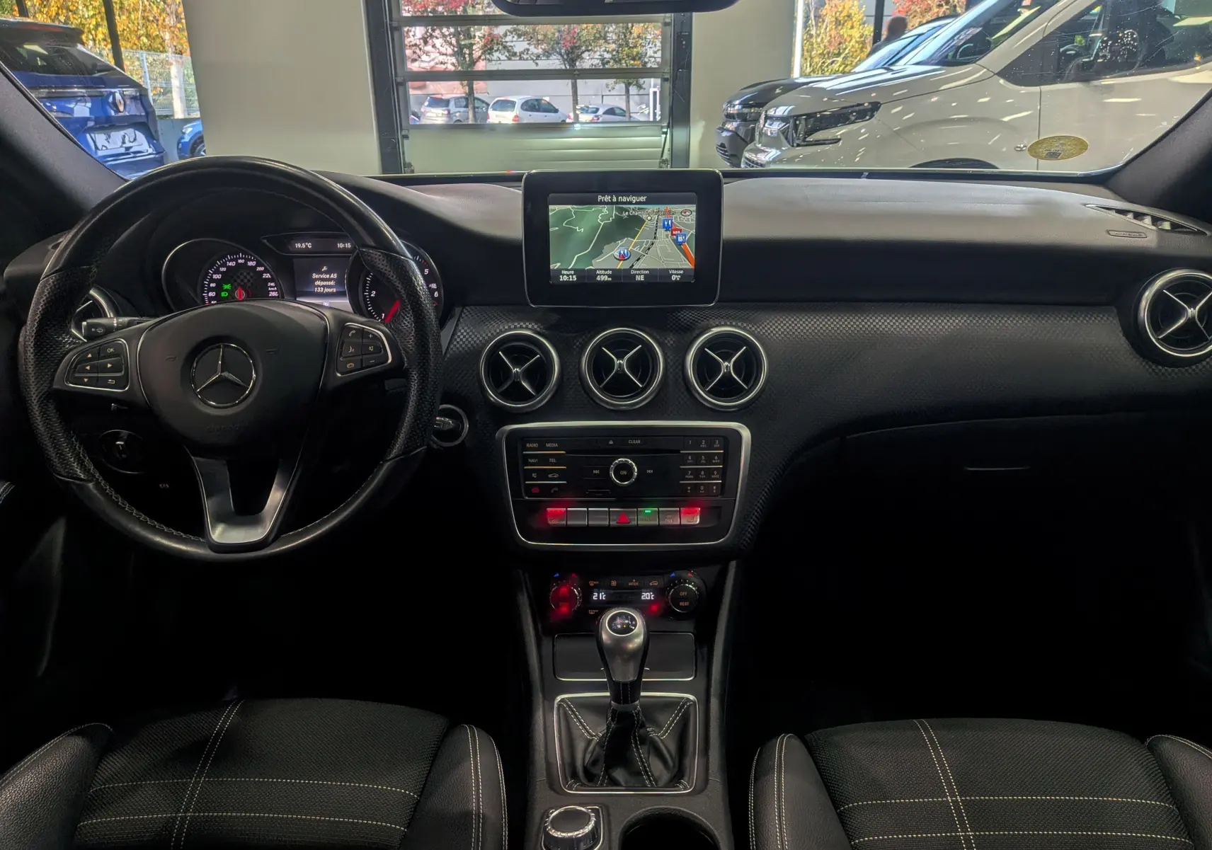 Vue intérieure du tableau de bord noir de la Mercedes Classe A 200d 2016 avec écran central et boîte manuelle.