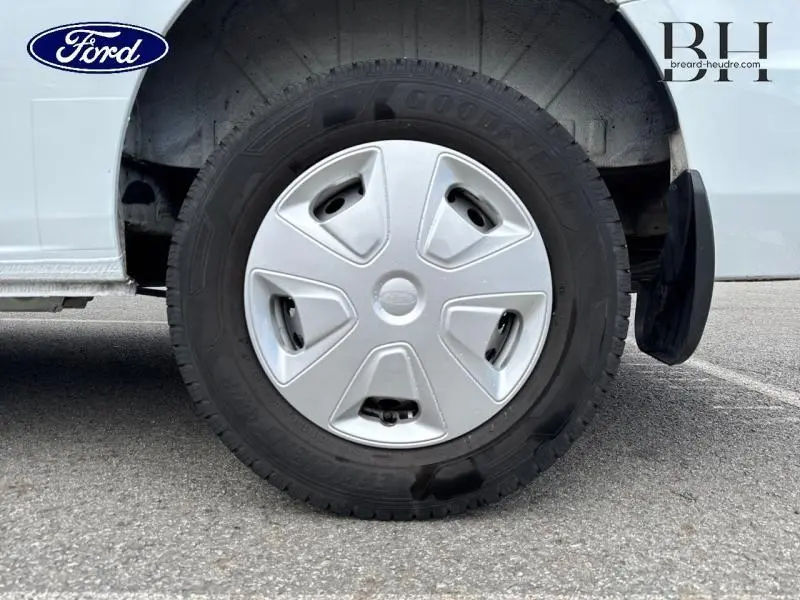 Gros plan sur la roue avant droite du Ford Transit Custom blanc Glacier, avec enjoliveur et bavette arrière visible.