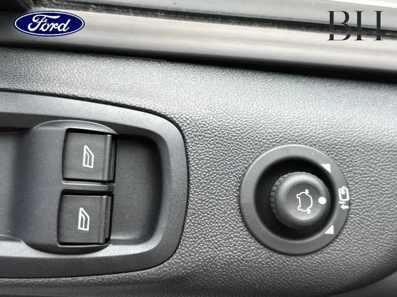 Gros plan sur les commandes de vitres électriques et réglage des rétroviseurs du Ford Transit Custom Fourgon blanc Glacier.