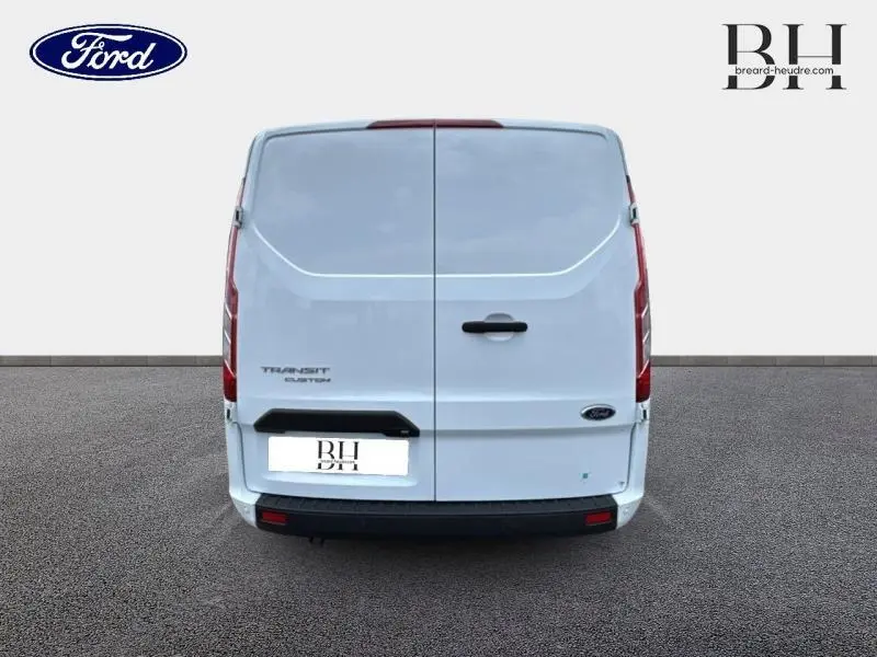 Vue arrière d'un Ford Transit Custom blanc Glacier, montrant les portes battantes fermées et les feux verticaux intégrés.