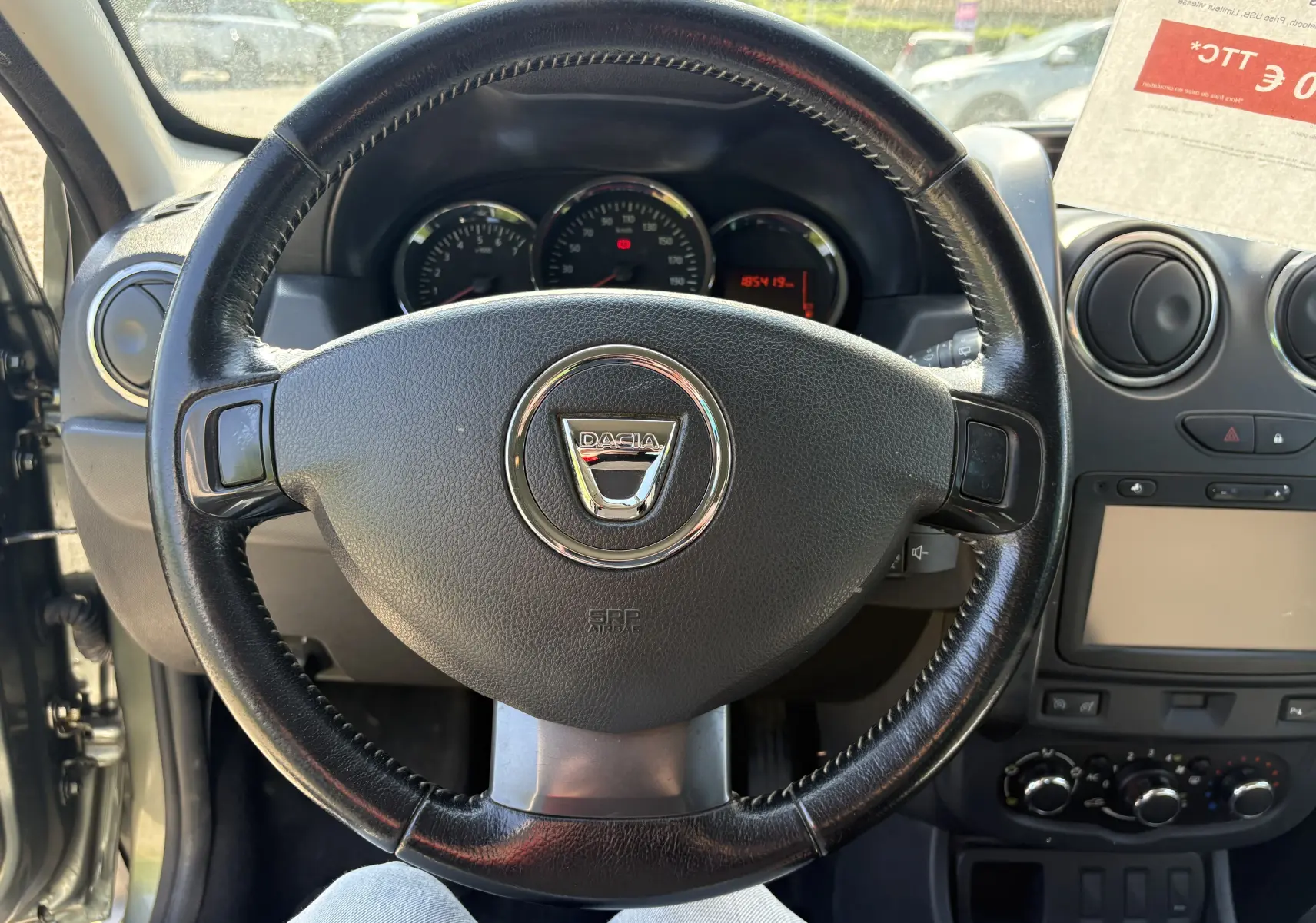 Vue intérieure centrée sur le volant noir du Dacia Duster 1.5 DCI 110 2014, avec tableau de bord et console centrale visibles.