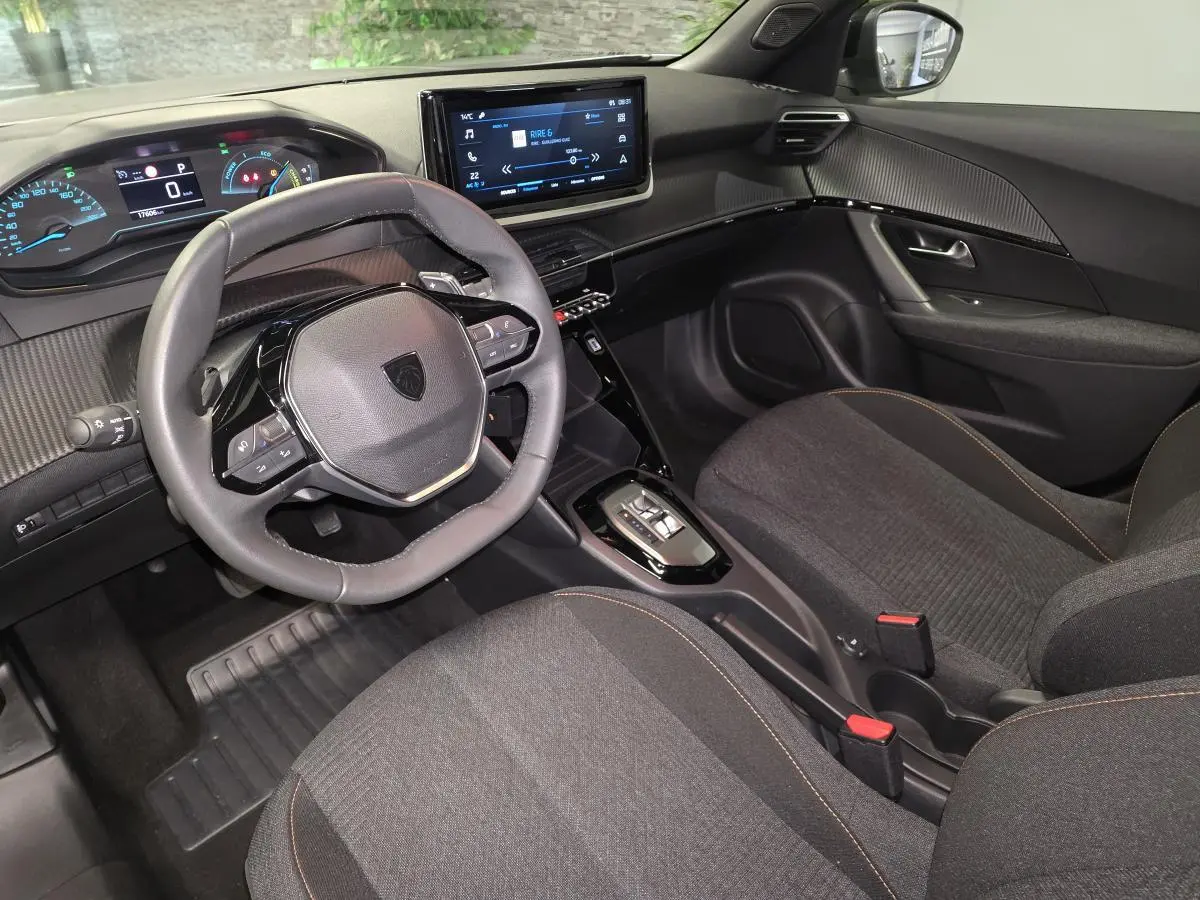 Intérieur avant droit du Peugeot 2008 gris 2025, volant compact cuir, tableau de bord numérique et écran tactile central.