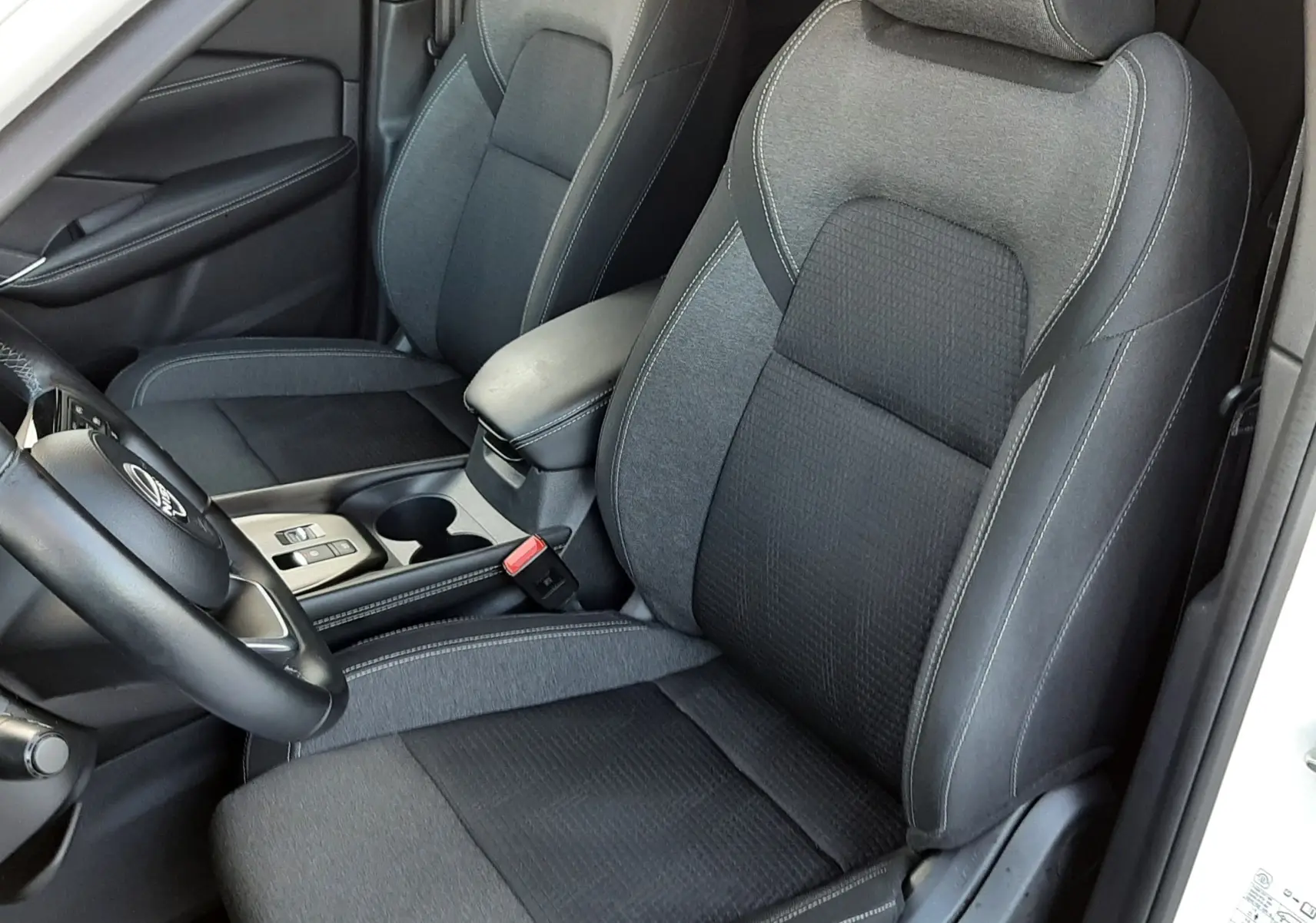 Vue intérieure rapprochée des sièges avant gris foncé et noir du Nissan Qashqai blanc lunaire 2022.