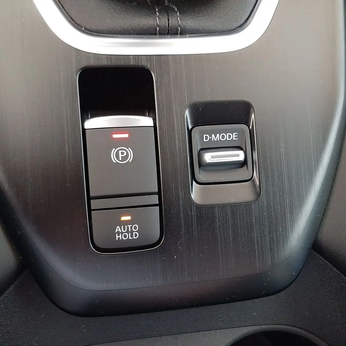 Gros plan sur la console centrale du Nissan Qashqai blanc lunaire 2022, avec boutons frein à main électronique et mode de conduite.