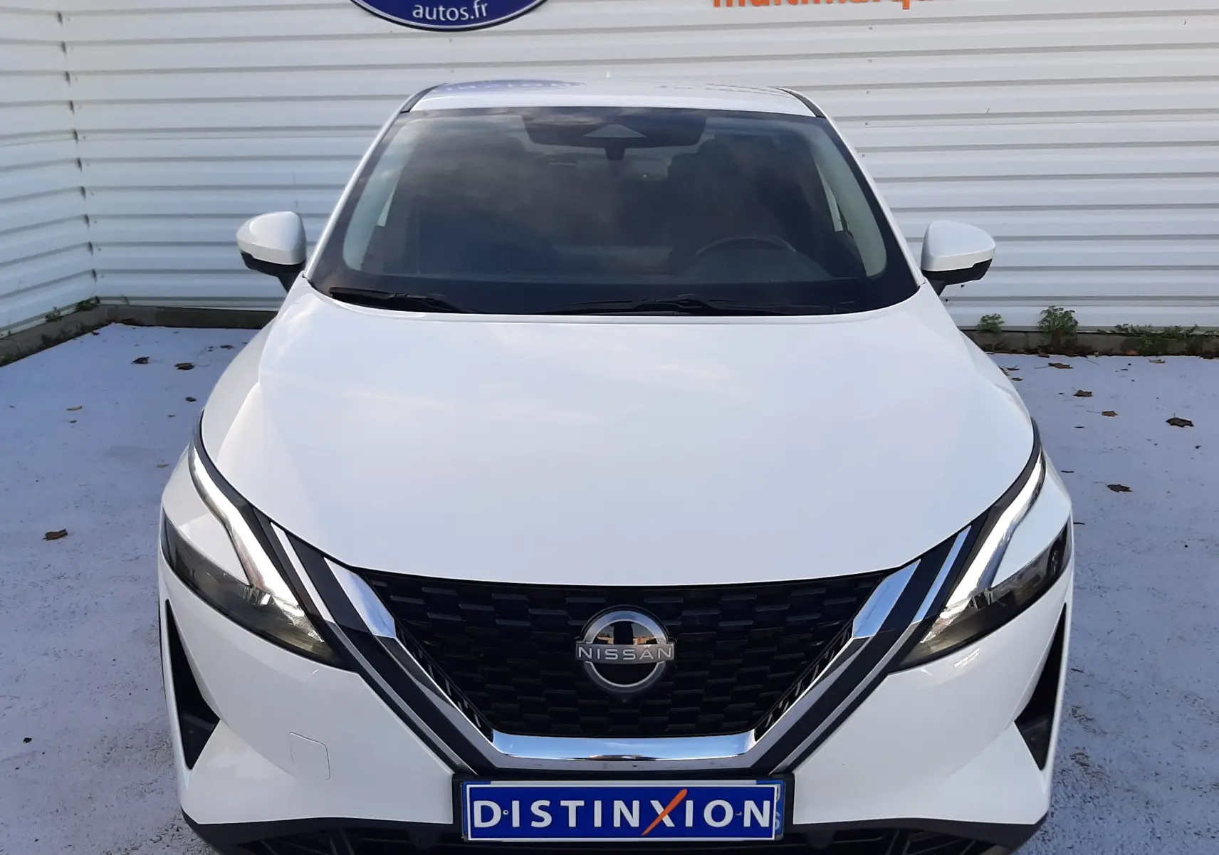 Vue frontale d'un Nissan Qashqai blanc lunaire 2022 avec calandre noire et logo chromé visible.