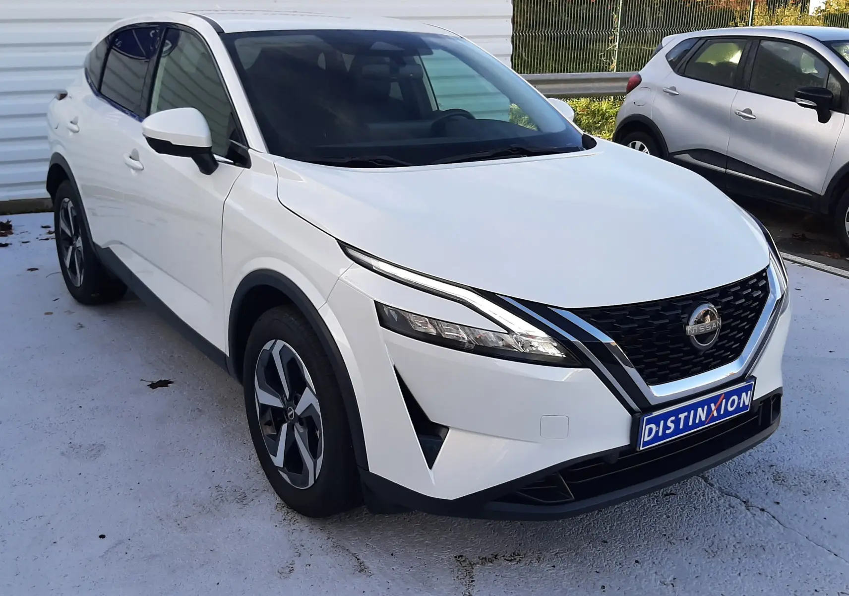 Vue 3/4 avant d'un Nissan Qashqai blanc lunaire 2022 avec calandre noire et jantes alliage distinctives.