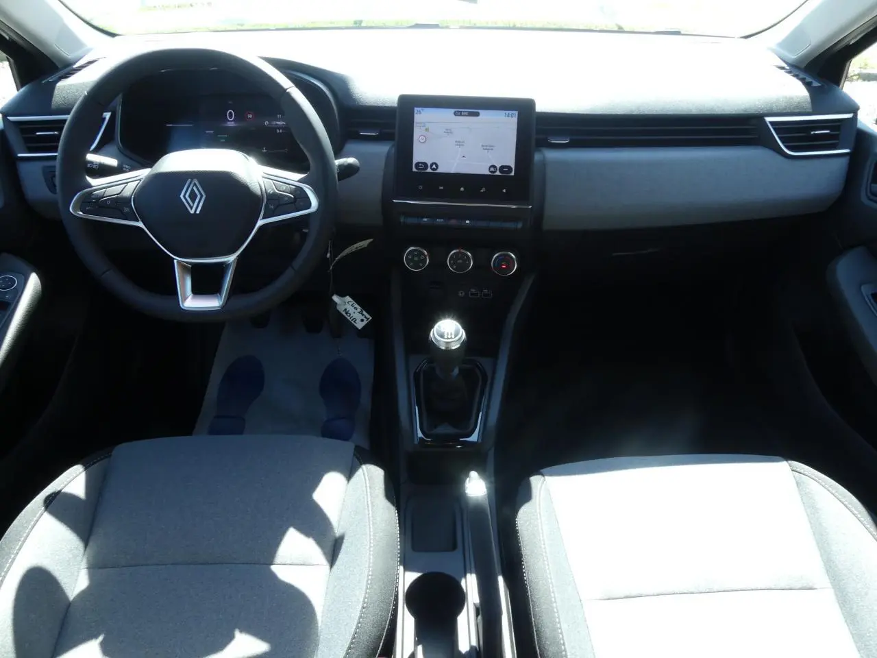 Vue intérieure avant de la Renault Clio 2025 montrant le volant multifonction, levier de vitesse manuel et écran tactile 7 pouces.