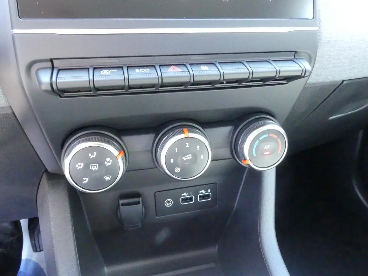 Gros plan sur les commandes de climatisation et boutons de fonction du tableau de bord de la Renault Clio noire 2025.