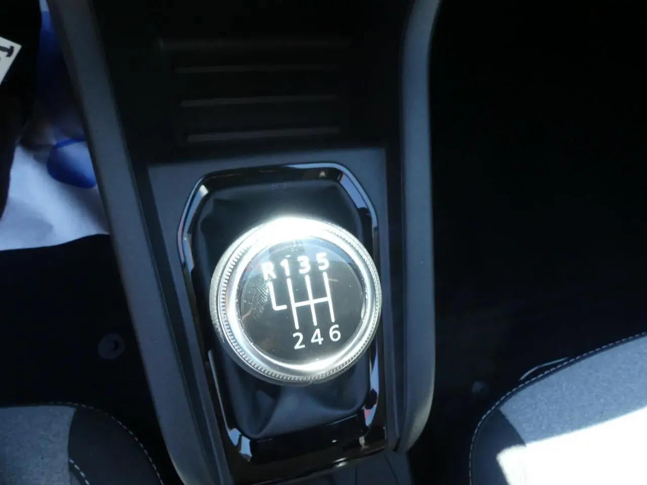 Gros plan sur le levier de vitesses manuel chromé de la Renault Clio noire, entouré de console noire brillante.