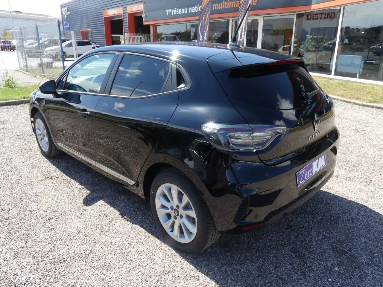 Renault Clio noire métallisée vue 3/4 arrière droit, avec feux arrière LED et jantes alliage visibles.