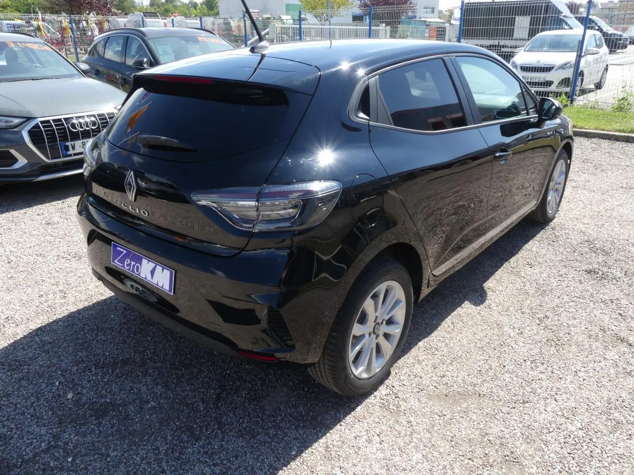 Renault Clio noir métallisé vue 3/4 arrière droit, avec feux arrière LED et jantes alliage visibles.