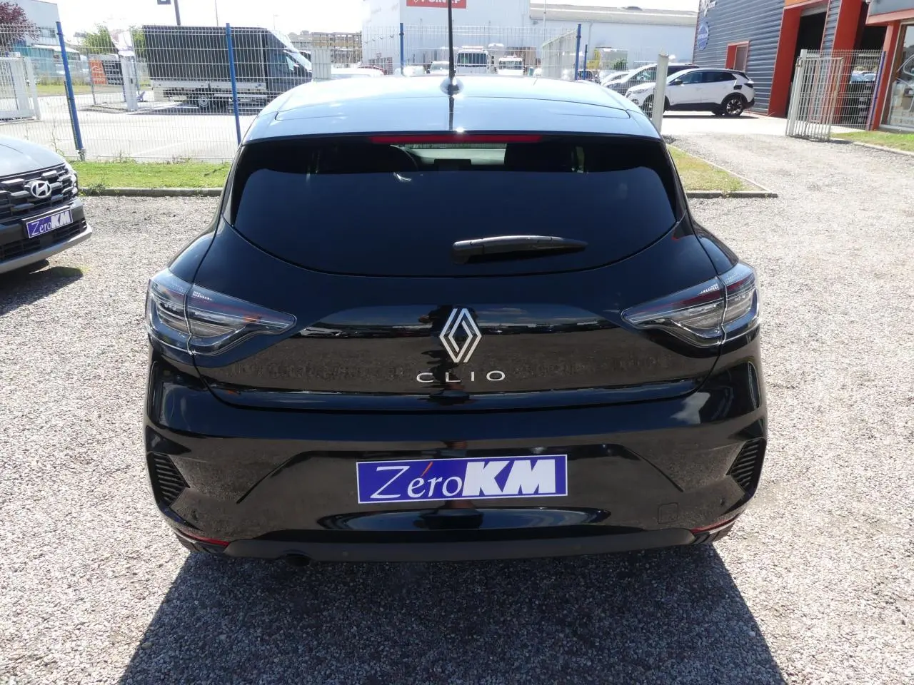 Vue arrière d'une Renault Clio noire métallisée 2025 avec feux arrière LED et logo Renault chromé visible.