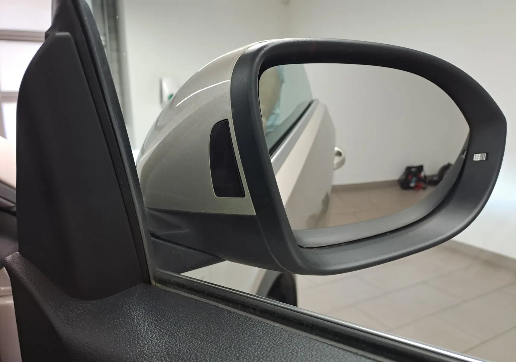 Rétroviseur extérieur côté gauche gris ivoire du Volkswagen T-Roc Cabriolet 2022 avec capote noire visible en reflet.