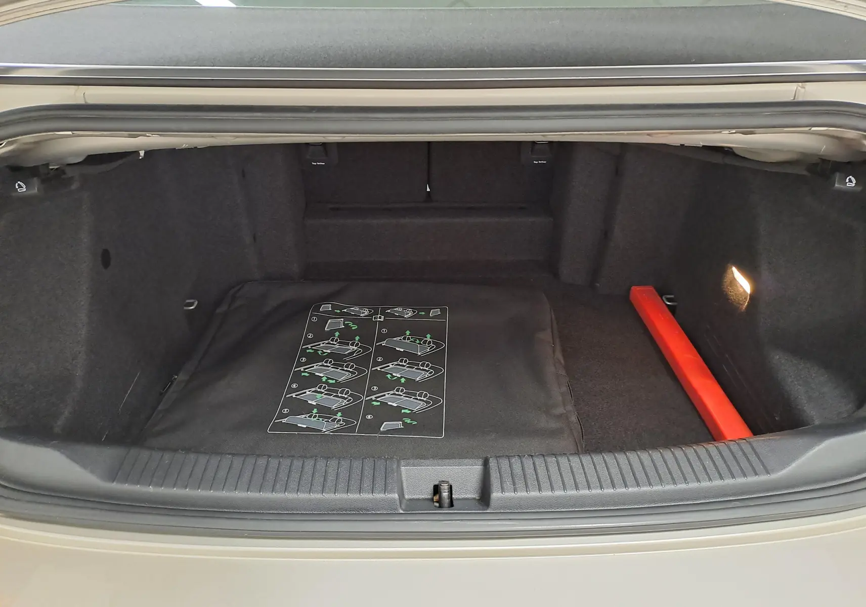 Coffre ouvert du Volkswagen T-Roc Cabriolet gris ivoire 2022, intérieur noir avec notice et triangle de sécurité rouge.
