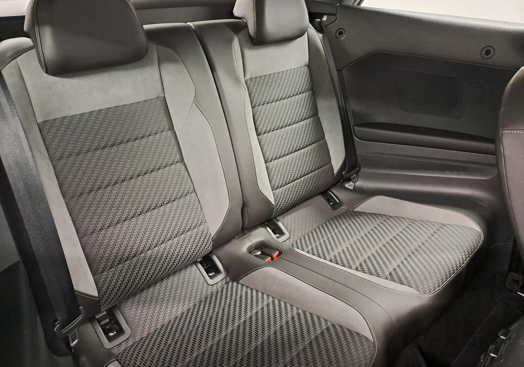 Vue rapprochée des sièges arrière en tissu gris et alcantara du Volkswagen T-Roc Cabriolet 2022 avec capote noire.